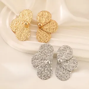 Detailed close-up of gold and silver alloy flower earrings with hammered metal texture