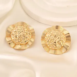 Macro detail of golden alloy flower earrings with vintage embossed hammer texture