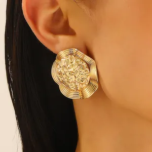 Detailed view of oversized golden alloy studs with hammered texture and sunburst ridges