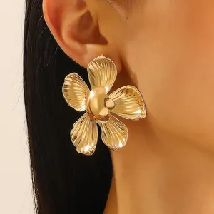 Close-up of golden alloy flower earring with radiant texture and polished finish on model