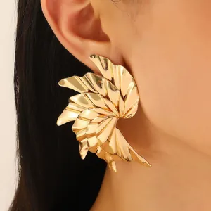 Macro detail of large gold floral earrings showing metallic texture and irregular wavy shape