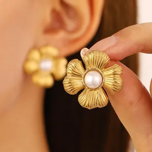 Macro view of gold flower earrings with petal texture and pearl center on the ear