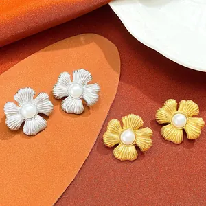 Detailed macro view of gold and silver flower earrings featuring smooth white pearls