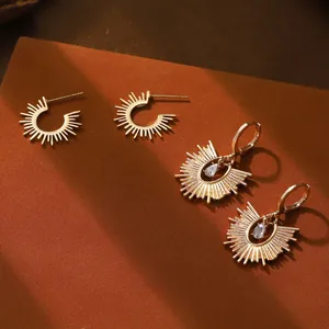 Dettaglio di orecchini a sole vintage con zircone a goccia e finitura oro caldo