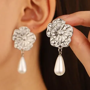 Close-up of vintage silver floral earrings with layered petals and white teardrop pearls