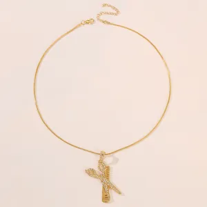 Detailed view of golden scissor and comb pendant with rhinestones and snake chain