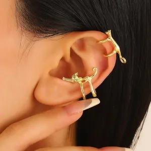 Close-up of golden cat-shaped ear cuffs with green zircon eyes on a model's ear