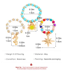 Detailed view of elastic beaded rings set with crab and seahorse charms and dimensions