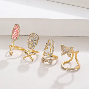 Detail view of four gold-plated knuckle rings with rhinestones and butterfly skull motifs