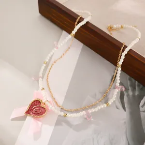 Detail of double-layer necklace with red heart pendant, pink bow and pearl beads