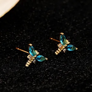 Detaillierte Makroaufnahme der goldenen Libellen-Ohrstecker mit blauen Zirkon-Steinen