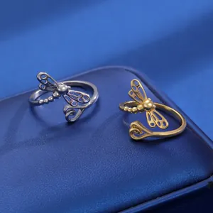 Detailansicht goldener und silberner Libellenringe mit hohlen Flügeln auf blauem Leder