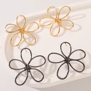 Detailed view of hollow floral earrings in gold and gunblack finishes on a display tray