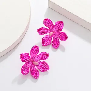 Vibrant pink oversized floral stud earrings with wavy texture petals on white display
