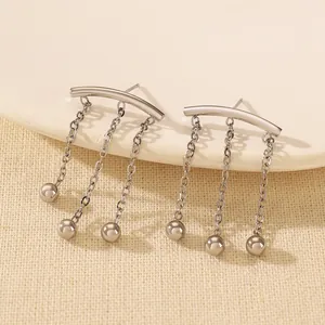 Close-up of polished silver fringe stud earrings with dangling chain tassels on a ceramic tray