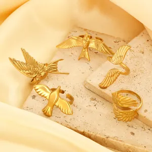Detail of adjustable gold-plated bird and feather rings set on a textured stone