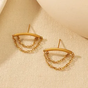 Close-up of golden stainless steel chain tassel stud earrings on a textured background