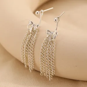 Macro view of silver bow earrings with hanging chain tassels in high-polished finish
