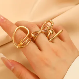 Nahaufnahme goldener geometrischer Ringe mit Schleifendesign auf Seidenstoff
