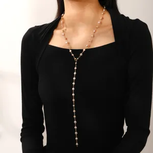 Verstellbare Y-förmige Goldkette mit weißen Perlen an einem Model in schwarzem Strick