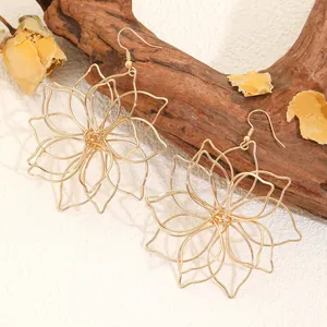 Detailansicht gewebter goldener Blumenohrringe mit mehreren Lagen auf rustikalem Holz