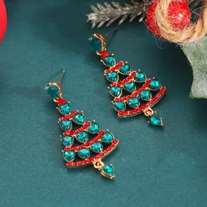 Close-up of gold Christmas tree earrings with green crystals and red rhinestones
