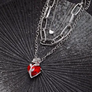 Detailed close-up of layered necklace with red heart crystal and silver rose thorn wrap