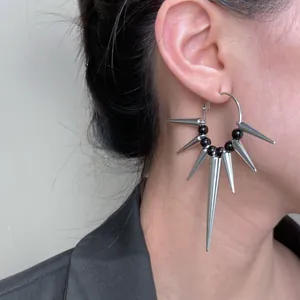 Close-up of punk style silver hoop earrings with long metallic spikes and black beads