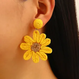 Handmade raffia sunflower earrings in bright yellow bohemian style on a model