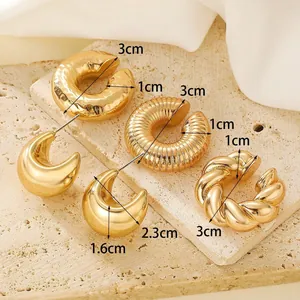 Détail de boucles d'oreilles créoles dorées avec textures lisses, ondulées et torsadées