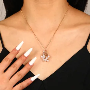Détail du collier doré avec pendentif grappe de perles et maillons fins sur la peau