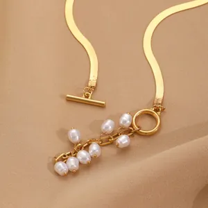 Détail du collier chaîne serpent dorée avec fermoir OT et pendentif en perles blanches