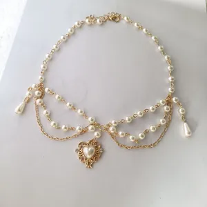Détail d'un collier de perles multicouche avec un pendentif cœur doré travaillé