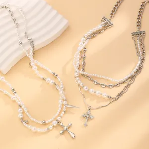 Détail de colliers de perles multicouches avec maillons argentés et pendentifs croix