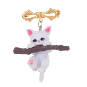 Broche chat blanc mignon sur une branche avec nœud doré et détails en résine