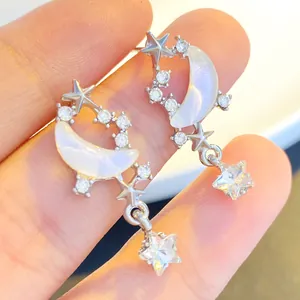 Detail view of silver star and moon earrings with cubic zirconia and iridescent pearls