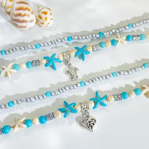 Dettaglio di collana bohémien con perline turchesi e ciondoli a tartaruga e cuore