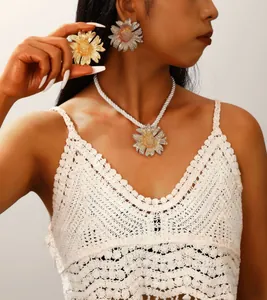 Detail of bohemian daisy jewelry set with gold metal petals and white twisted rope necklace