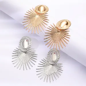 Détail macro de boucles d'oreilles géométriques en forme d'éventail dorées et argentées