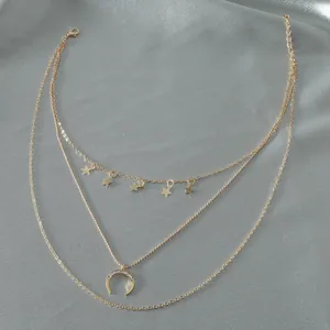 Three-layer gold necklace with star charms and rhinestone moon pendant on silver silk