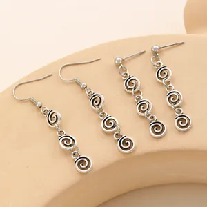 Detalle macro de pendientes étnicos vintage con diseño geométrico de espiral en aleación