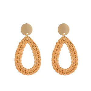 Close-up of bohemian water-drop woven rattan earrings with gold plated circular studs
