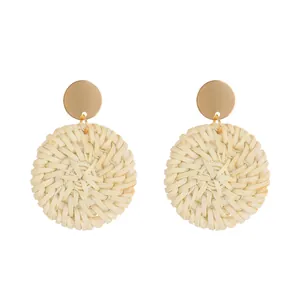 Detailed close-up of woven rattan hoop earrings with gold metallic circular studs