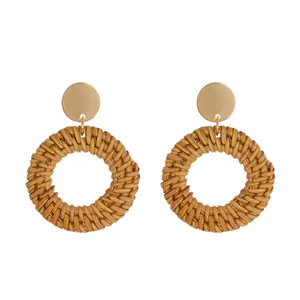 Detailed view of bohemian woven rattan hoop earrings with gold-toned round metallic studs