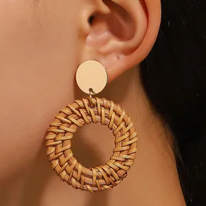 Bohemian rattan woven hoop earrings with golden metallic studs on a female model