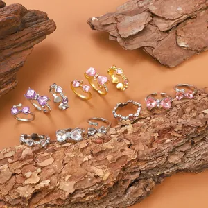 Anillos chic con corazón rosa y lazo en oro y plata sobre base de madera natural