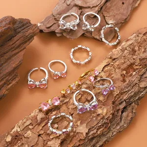 Primer plano de anillos con corazón rosa y lazo con circonitas en madera real