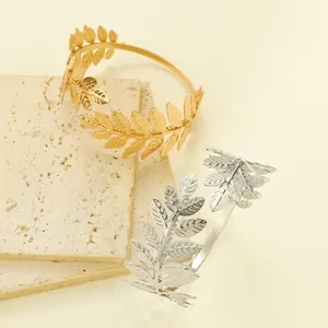 Detailed view of gold and silver leaf-shaped open arm cuffs with vintage vein texture