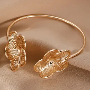 Close-up of golden leaf bangle with detailed dual flower design on champagne fabric