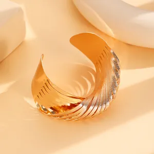 Detailed macro view of gold layered cuff bracelet with textured metallic finishes